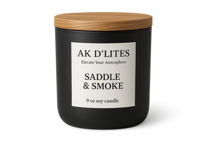 black matte candle jar with a white label and light brown wooden lid with AK D'LITES logo below the logo in a smaller font Elevate Your Atmosphere with the scent SADDLE & SMOKE and at the bottom in a smaller font 9 oz soy candle Transparent background
